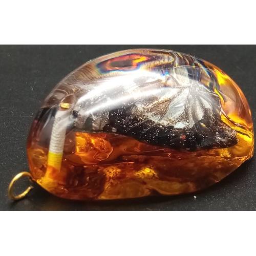 238 - Two large resin amber pendants with a butterfly inclusion. App 6 cm long.