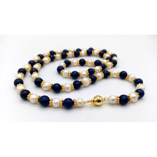 455 - A Lapis Lazuli and Cultured Pearl Matinee Necklace. 70cm. Gold plated spacers and clasp.