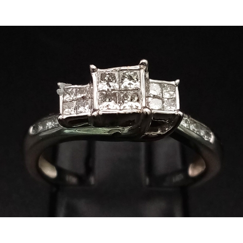 141 - A 10K White Gold Diamond Ring. Three squares of Princess-cut diamonds supported by round-cut diamond... 