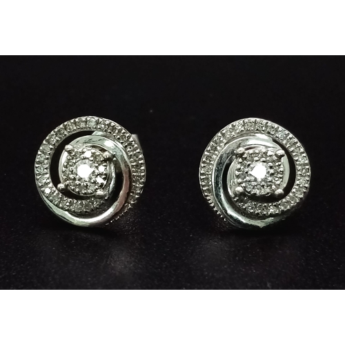 1186 - A Pair of 9K White Gold and Diamond Swirl-Stud Earrings. 1.67g total weight. Ref: 53