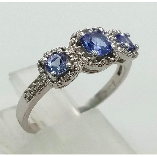 377 - A 9k White Gold Tanzanite Trilogy and Diamond Ring. Three bright, clean tanzanites with small diamon... 