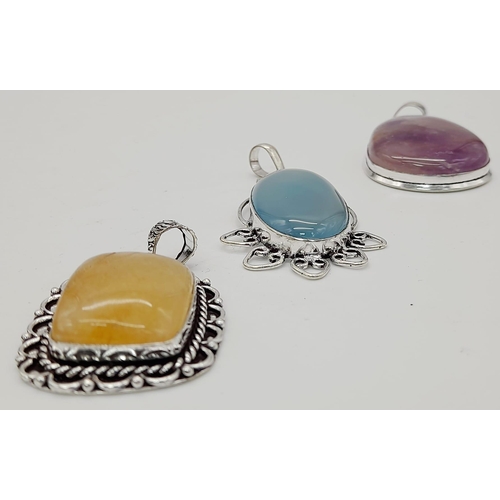 562 - Three Vividly Coloured GemStone Pendants set in Decorative White Metal. Largest - 6cm.