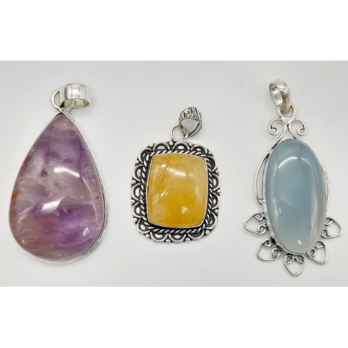 562 - Three Vividly Coloured GemStone Pendants set in Decorative White Metal. Largest - 6cm.