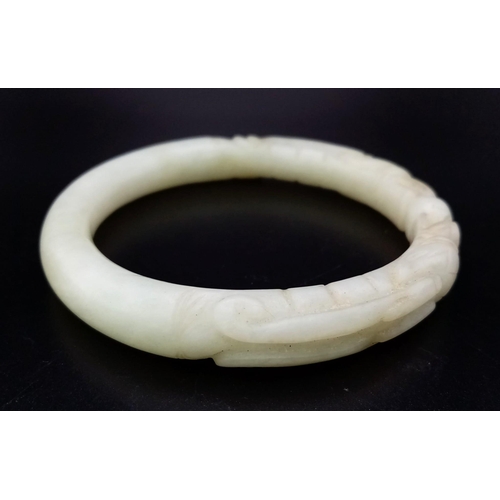 570 - An Antique Chinese Pale Green Dragon-Head Jade Bangle. Hand-carved double dragon head design. 65mm i... 