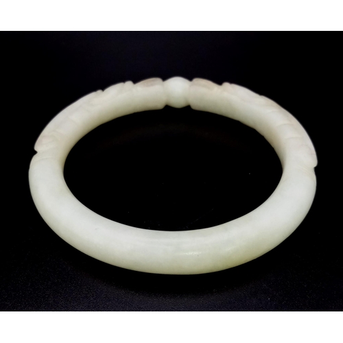 570 - An Antique Chinese Pale Green Dragon-Head Jade Bangle. Hand-carved double dragon head design. 65mm i... 