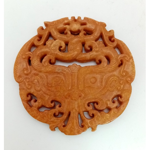 740 - An antique, Chinese, hand carved orange jade amulet on a custom made wooden carved base. The amulet ... 