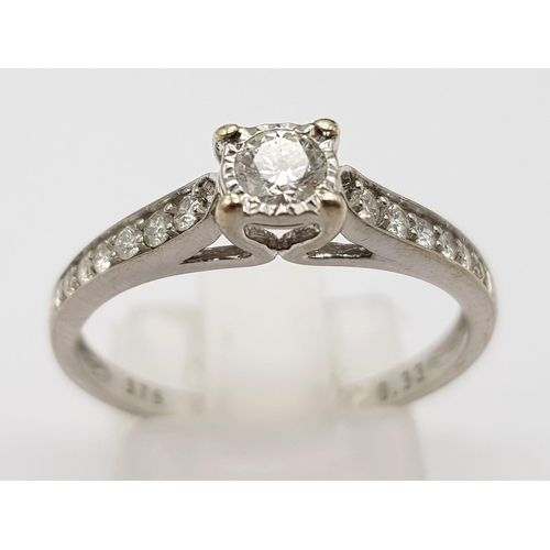 654 - A 9K White Gold Diamond Ring. 0.33ct. Central round cut diamond with complimentary smaller diamonds ... 