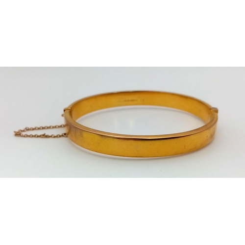 1317 - A Vintage 9K Yellow Gold Bangle. Clip opening with safety chain. Scrolled decoration. 6cm inner diam... 