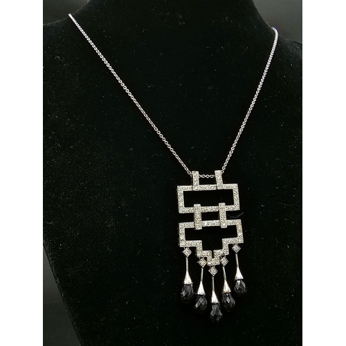 79 - An 18K White Gold Garnet and Diamond Pendant on an 18K White Gold Necklace. An art deco style pendan... 