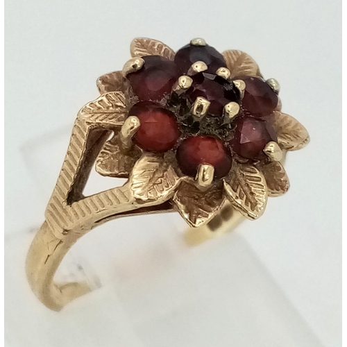 665 - A Vintage 9K Yellow Gold Garnet Ring. Floral decoration. Size K. 2.43g total weight.