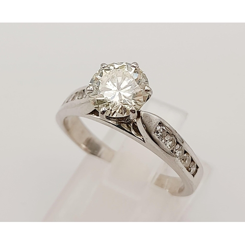 127 - A 14 K white gold ring with a brilliant cut diamond and other diamonds on the shoulders of the ring.... 