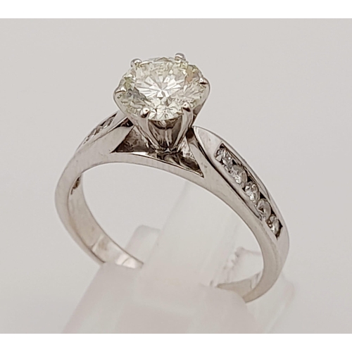 127 - A 14 K white gold ring with a brilliant cut diamond and other diamonds on the shoulders of the ring.... 