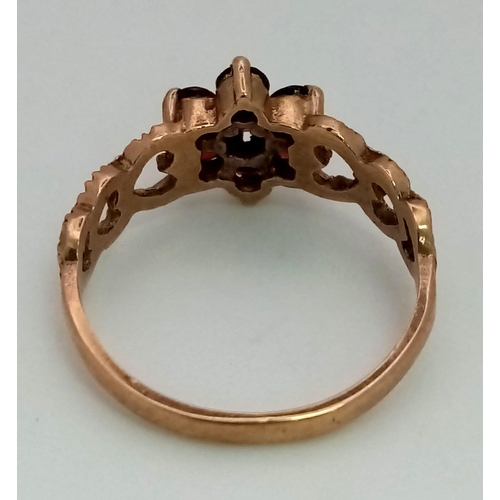 1290 - A Vintage 9K Yellow Gold Garnet Love Ring. Floral garnet central design with heart decoration either... 