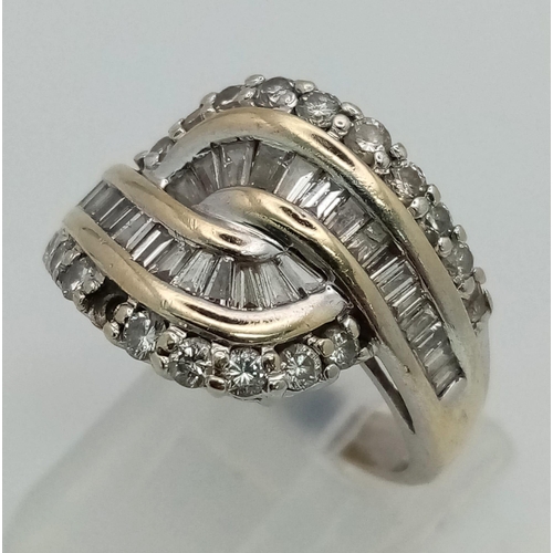 462 - An 18K White Gold Diamond Crossover Ring. Baguette and round cut diamond crossover. Note: one small ... 