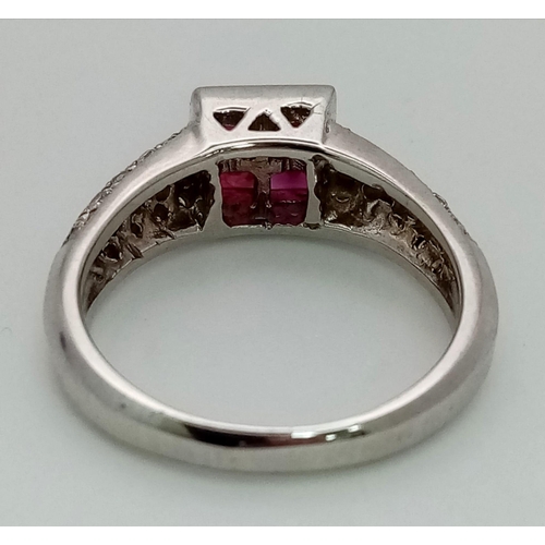 701 - An 18K White Gold Diamond and Ruby Ring. Four square-cut central rubies with a three row cluster of ... 