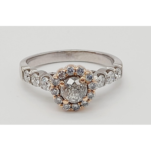 437 - An 18K White and Rose Gold Diamond Ring. A central 0.70ct diamond surrounded by a halo, wings and fo... 