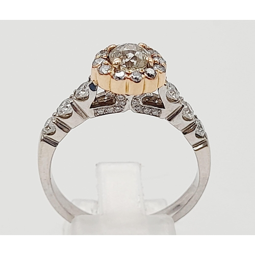 437 - An 18K White and Rose Gold Diamond Ring. A central 0.70ct diamond surrounded by a halo, wings and fo... 