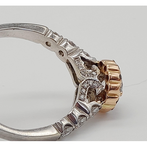 437 - An 18K White and Rose Gold Diamond Ring. A central 0.70ct diamond surrounded by a halo, wings and fo... 