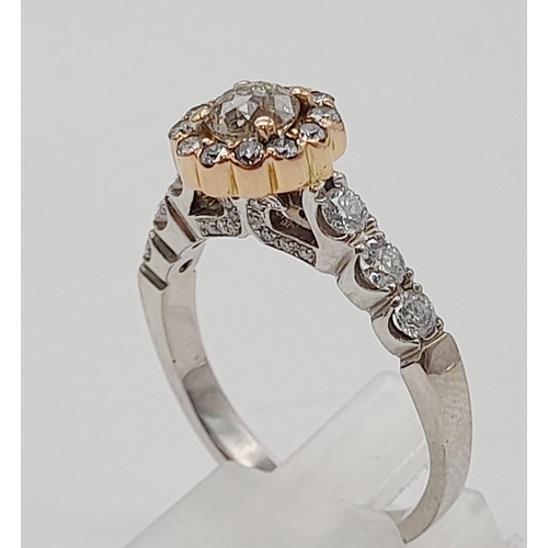 437 - An 18K White and Rose Gold Diamond Ring. A central 0.70ct diamond surrounded by a halo, wings and fo... 