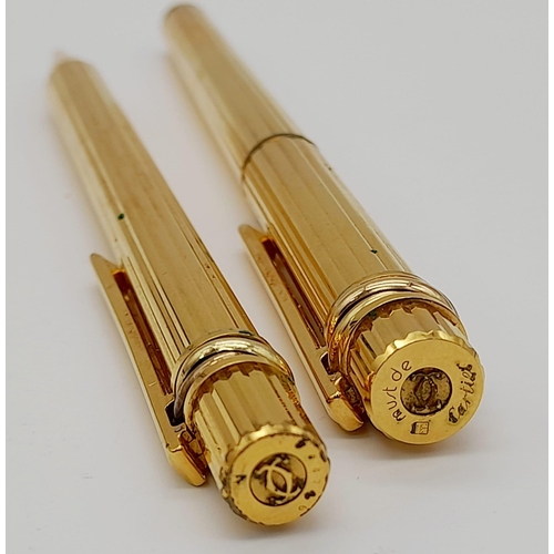 520 - A Set of Two Gold Plated Cartier Pens. A rollerball and ballpoint. Presented in a leather burgundy p... 