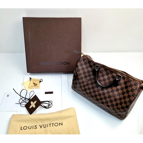 534 - A Louis Vuitton Speedy Bag. Monogram brown canvas. Brown leather handles. Plush red cloth interior. ... 