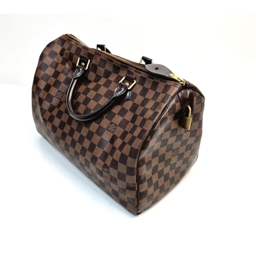 534 - A Louis Vuitton Speedy Bag. Monogram brown canvas. Brown leather handles. Plush red cloth interior. ... 