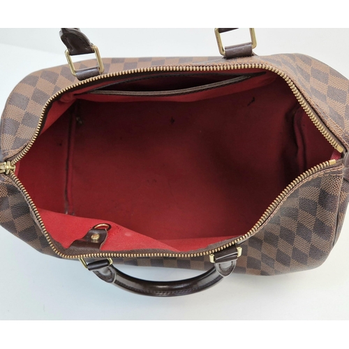 534 - A Louis Vuitton Speedy Bag. Monogram brown canvas. Brown leather handles. Plush red cloth interior. ... 