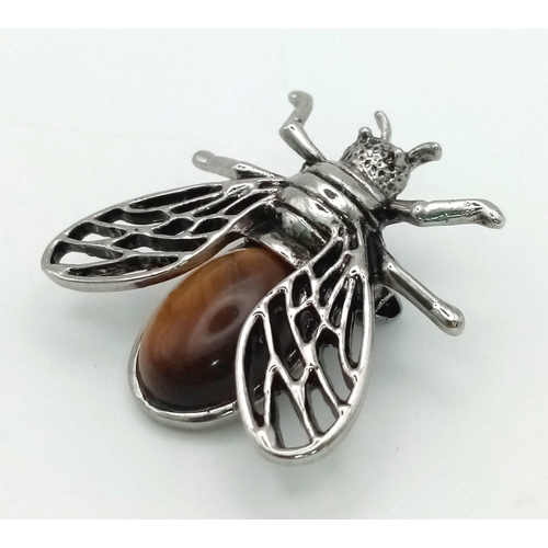 1263 - A Tigers Eye Bee Brooch. Set in white metal. 4cm x 3.5cm wingspan.