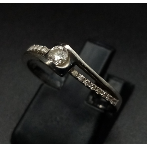 717 - 18K WHITE GOLD DIAMOND SOLITAIRE TWIST RING.  0.20CT DIAMOND. TOTAL WEIGHT  2.2G.  SIZE M