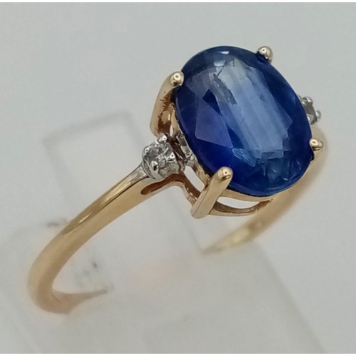 1188 - A 9K Yellow Gold Sapphire and Diamond Ring. Central oval sapphire with a small round cut diamond eit... 