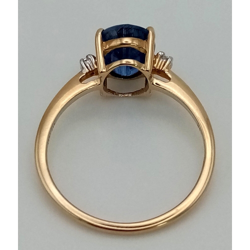 1188 - A 9K Yellow Gold Sapphire and Diamond Ring. Central oval sapphire with a small round cut diamond eit... 