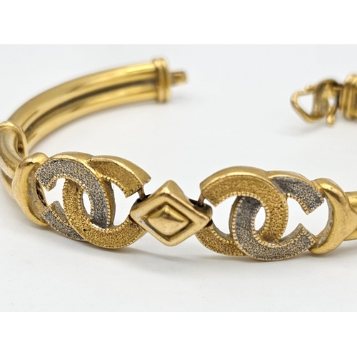 371 - A 22k yellow gold lot consisting of a bangle with Two CC ornaments and a chain necklace with a heart... 