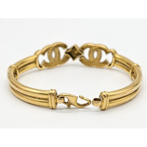 371 - A 22k yellow gold lot consisting of a bangle with Two CC ornaments and a chain necklace with a heart... 