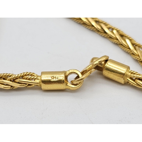 371 - A 22k yellow gold lot consisting of a bangle with Two CC ornaments and a chain necklace with a heart... 