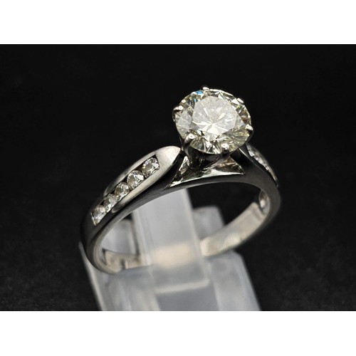 127 - A 14 K white gold ring with a brilliant cut diamond and other diamonds on the shoulders of the ring.... 