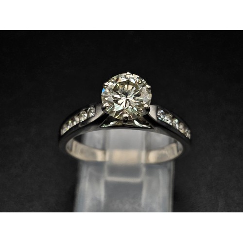 127 - A 14 K white gold ring with a brilliant cut diamond and other diamonds on the shoulders of the ring.... 