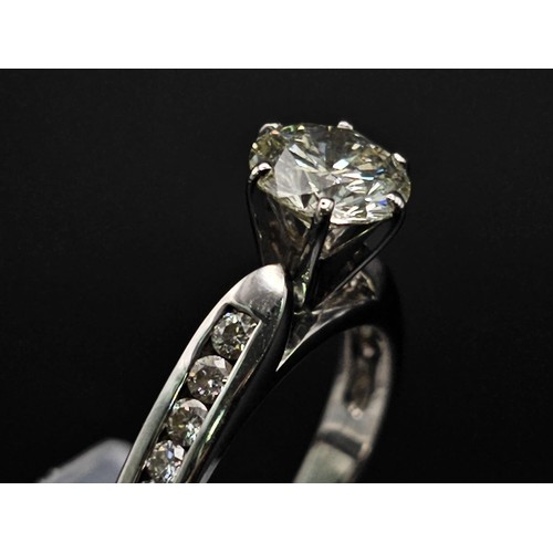 127 - A 14 K white gold ring with a brilliant cut diamond and other diamonds on the shoulders of the ring.... 