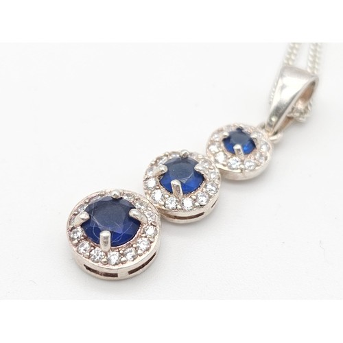 1459 - A SIMPLY SILVER NECKLACE AND PENDANT WITH 3 GRADUATED BLUE STONES SET IN SILVER AND SURROUNDED BY ZI... 