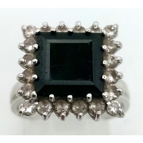 45 - An 18K White Gold Emerald and Diamond Ring. Square-cut dark green emerald with a white diamond surro... 