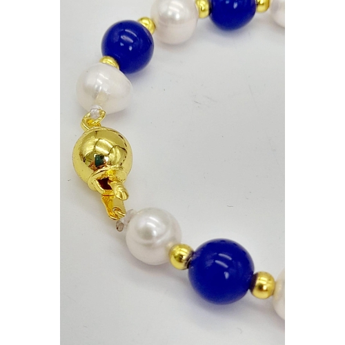 1109 - A Lapis Lazuli and Cultured Pearl Bracelet. Gilded spacers and clasp.