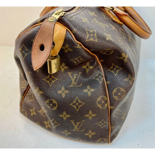 67 - A Louis Vuitton Monogram Speedy Canvas Bag. Gold-tone hardware. Leather trim and handles. Brown text... 