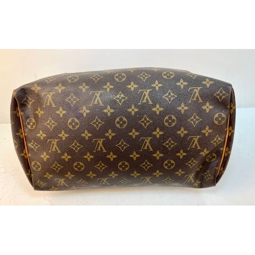 67 - A Louis Vuitton Monogram Speedy Canvas Bag. Gold-tone hardware. Leather trim and handles. Brown text... 