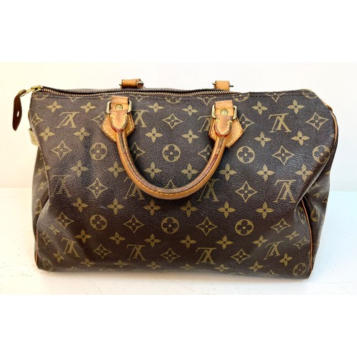 67 - A Louis Vuitton Monogram Speedy Canvas Bag. Gold-tone hardware. Leather trim and handles. Brown text... 