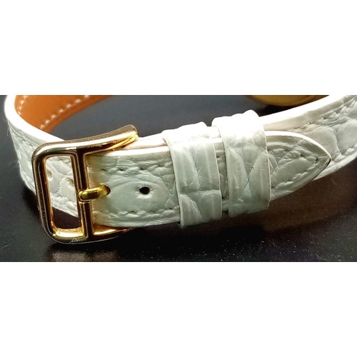 123 - A HERMES 18K GOLD LADIES WRISTWATCH WITH DESIGNER BEZEL, WHITE DIAL , ROMAN NUMERALS ON A WHITE LEAT... 