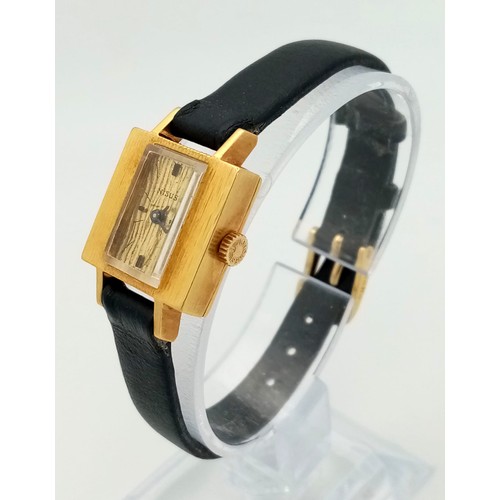 137 - A Vintage Nisus 18K Gold Ladies Watch. Black leather strap. Square 18K gold case with bark-effect de... 