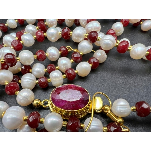 231 - A very elegant, opera length necklace and earrings set with natural white pearls and faceted rubies,... 