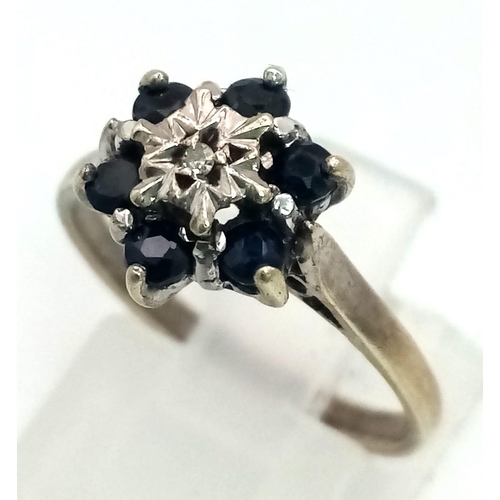 871 - A 9K White Gold Sapphire and Diamond Ring. Six sapphires with a small central diamond. Size M. 2.64g... 