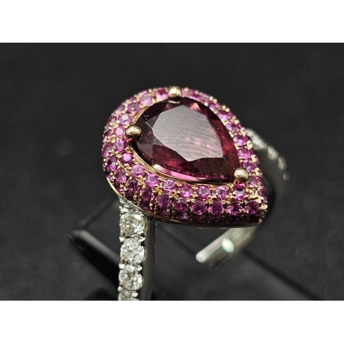 174 - An extraordinary 18 K white gold ring with a central pear cut rubelite  (3 carats appr), surrounded ... 