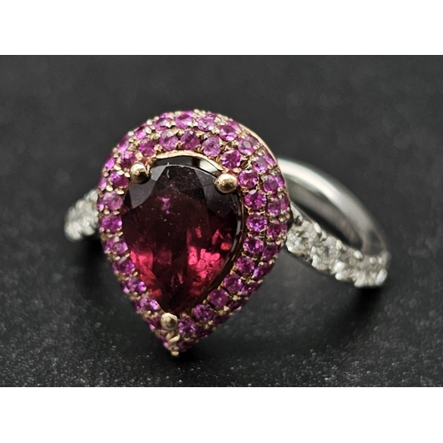 174 - An extraordinary 18 K white gold ring with a central pear cut rubelite  (3 carats appr), surrounded ... 