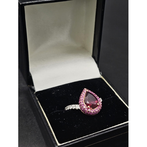 174 - An extraordinary 18 K white gold ring with a central pear cut rubelite  (3 carats appr), surrounded ... 